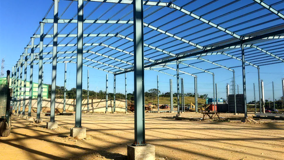 Charpente métallique en cours de montage sur un chantier CHARMETAL : portiques et pannes posés sur massifs béton